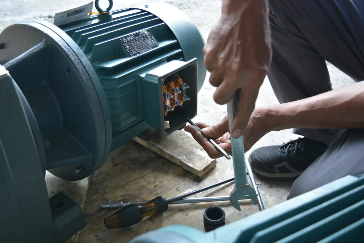 Técnico ajustando con una llave la caja de conexiones de un motor eléctrico